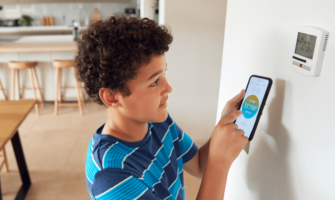 Child looking at thermostat controlled by phone